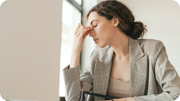 Женщина сидит за столом и трет глаза от усталости