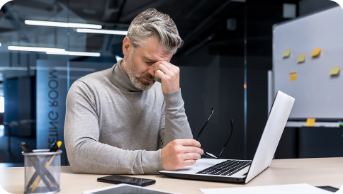 Мужчина за компьютером трет глаза от усталости